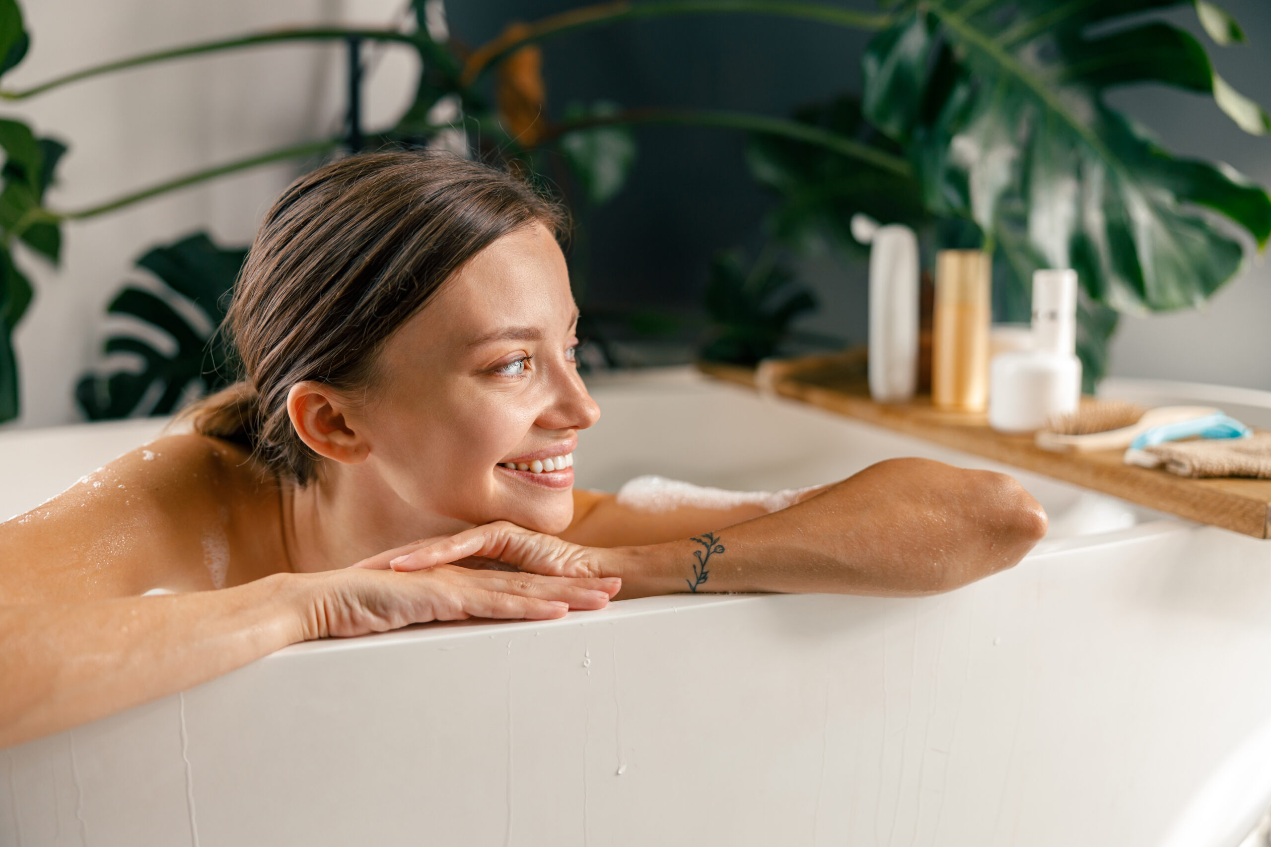 Portrait of happy young woman smiling aside while resting in bathtub at luxury spa resort