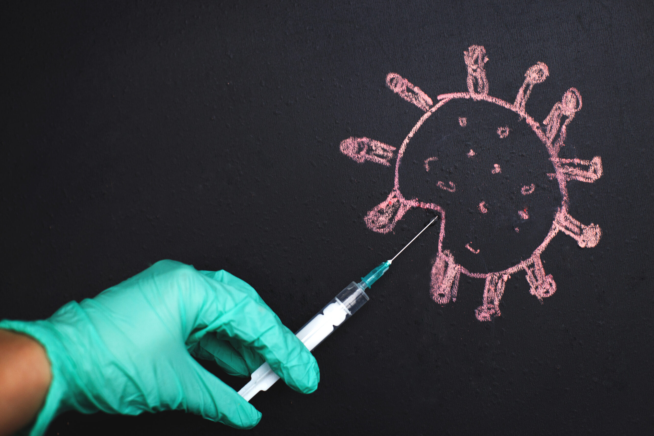 the doctor's hand makes an injection into the coronavirus molecule. The concept of defeating the virus by vaccination.